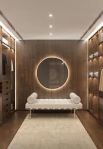 Luxueux dressing en bois foncé avec miroir rond lumineux et banquette blanche. Placards intégrés et éclairage LED moderne.