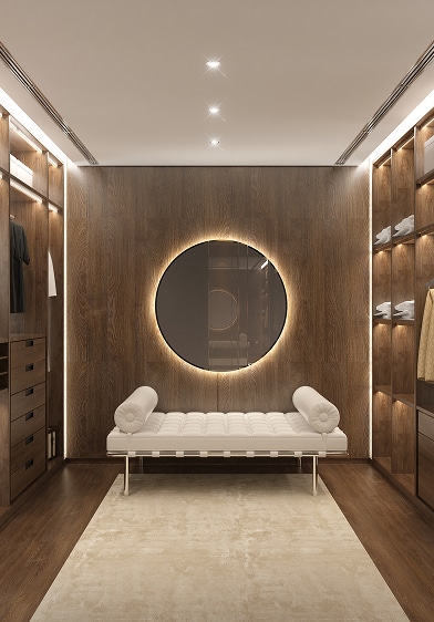 Luxueux dressing en bois foncé avec miroir rond lumineux et banquette blanche. Placards intégrés et éclairage LED moderne.