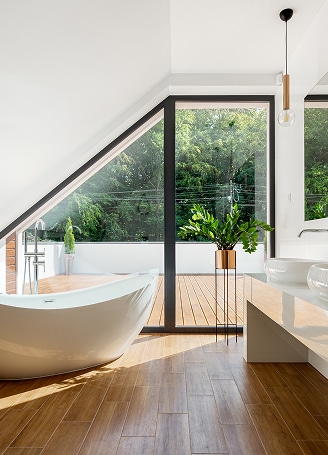 Salle de Bain Design : Baignoire Moderne et Vue Nature Apaisante Salle de bain moderne lumineuse avec baignoire blanche sur pied, parquet en bois et grande fenêtre offrant une vue sur la nature.